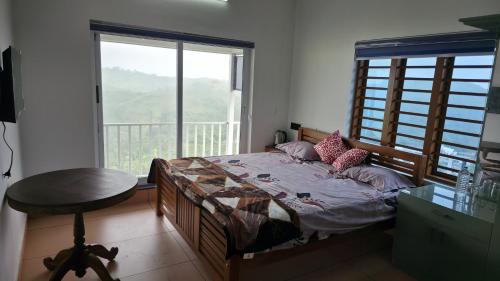 een slaapkamer met een bed, een tafel en een raam bij Metro Heights in Parunthumpara