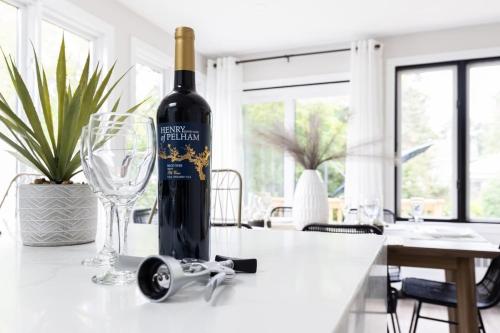 een fles wijn zittend op een tafel met een glas bij New Modern Home in Old Town in Niagara on the Lake
