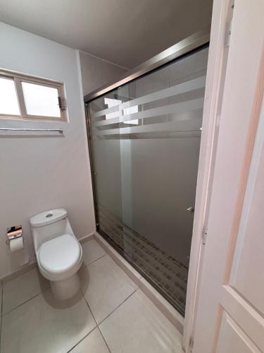 a bathroom with a toilet and a glass shower at Residencia Flores in Hermosillo