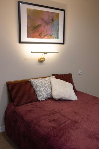 a bedroom with a red bed with a picture on the wall at Apartamenty obok Suntago Park of Poland parking gratis in Wręcza