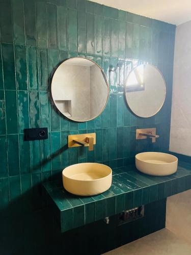 two sinks in a green tiled bathroom with mirrors at Bungalow in Marrakech in Marrakesh