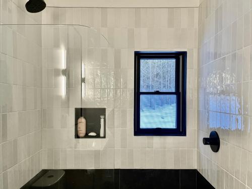 bagno piastrellato bianco con finestra e servizi igienici di White Pine Chalet a Yulan