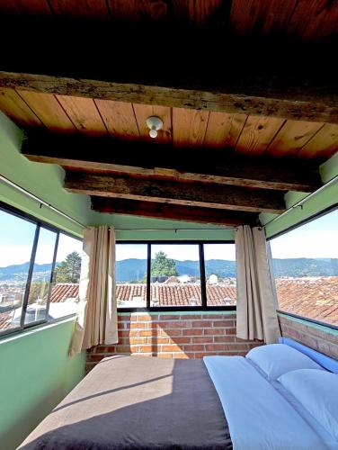 a bedroom with a bed in a room with windows at Hostal La Isla in San Cristóbal de Las Casas