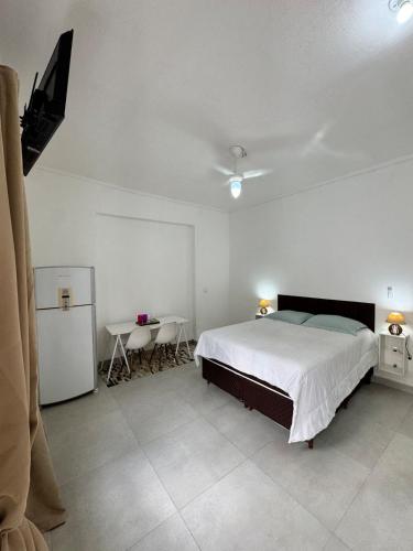 a bedroom with a bed and a table and a tv at Suite 1 com Ar-Condicionado, TV, Wi-Fi e Geladeira in Jundiaí