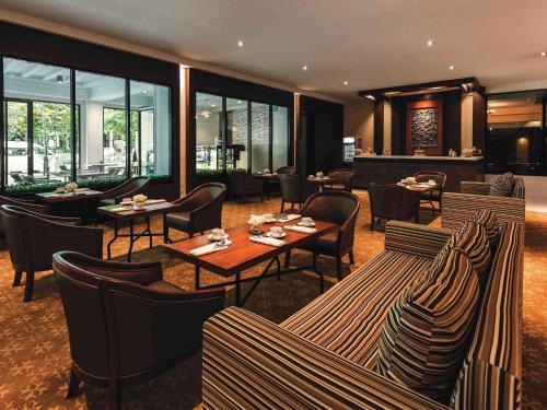 un restaurant avec des tables, des chaises et des fenêtres dans l'établissement Movenpick Suriwongse Hotel Chiang Mai, à Chiang Mai