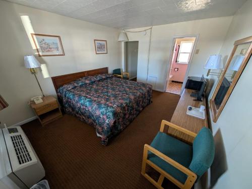 ein Hotelzimmer mit einem Bett und einem Stuhl in der Unterkunft Relax Inn in New Castle