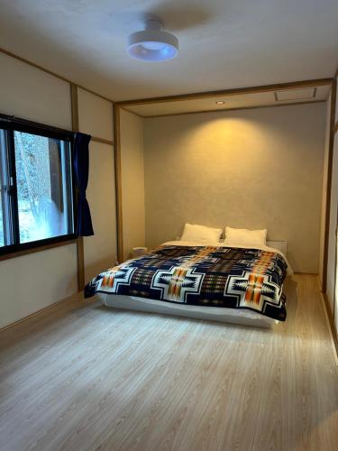 a bedroom with a bed and a window at Pebble Mountain Cabin in Shinano