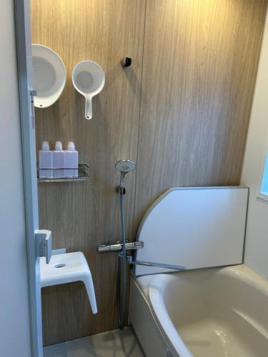 a bathroom with a white tub and a sink at Pebble Mountain Cabin in Shinano