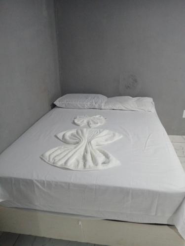ein weißes Bett mit Blumenmuster darauf in der Unterkunft Kitnet na mata atlantica in Ubatuba