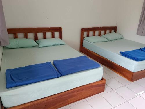 two beds in a room with blue pillows at บ้านไร่เรืองแสง in Ban Thung Samo