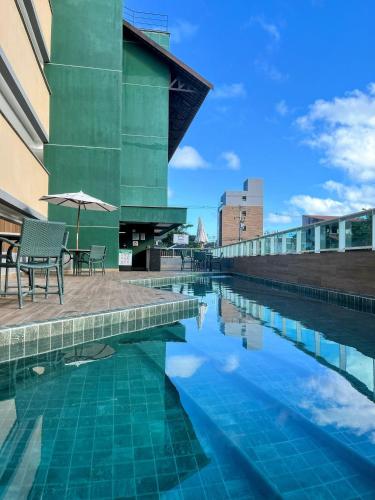 een zwembad met ligstoelen en een parasol naast een gebouw bij Cupe Living - VSH in Porto De Galinhas