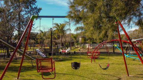 a playground with swings and slides in a park at Cabañas Villa Fariña in Gualeguaychú