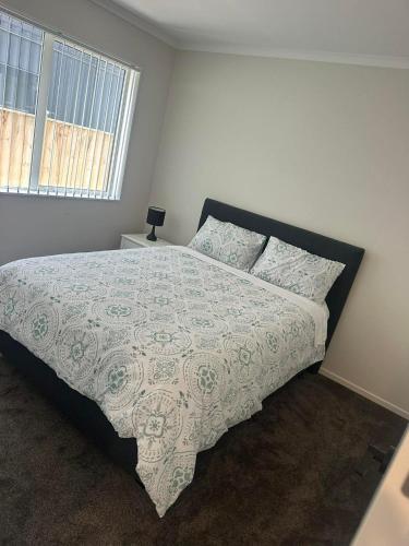 a bedroom with a large bed with a comforter and a window at Bula Suite Flatbush New Zealand - Granny Flat in Auckland