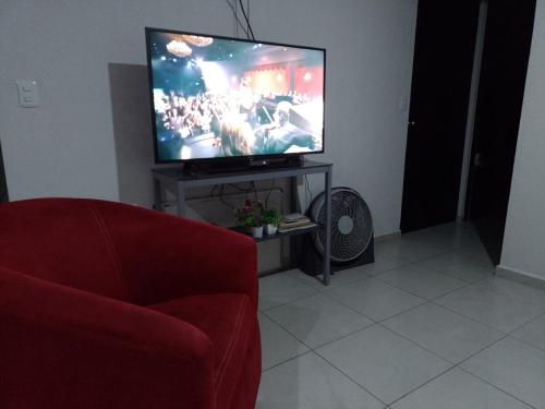 a living room with a tv and a red chair at Apartment 5 minutes away from AICM, GNP in Mexico City