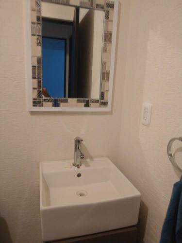 a white sink in a bathroom with a mirror at Apartment 5 minutes away from AICM, GNP in Mexico City
