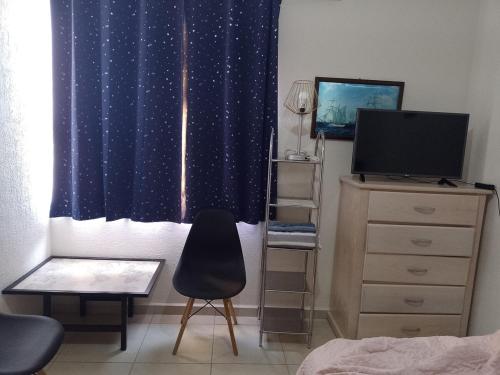 a bedroom with a bed and a chair and a television at Apartment 5 minutes away from AICM, GNP in Mexico City