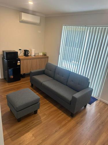 a living room with a blue couch and a ottoman at Bula Suite Flatbush New Zealand - Granny Flat in Auckland