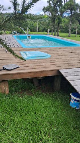 a wooden deck next to a swimming pool at Refúgio Serrano - Cabana in São Francisco de Paula