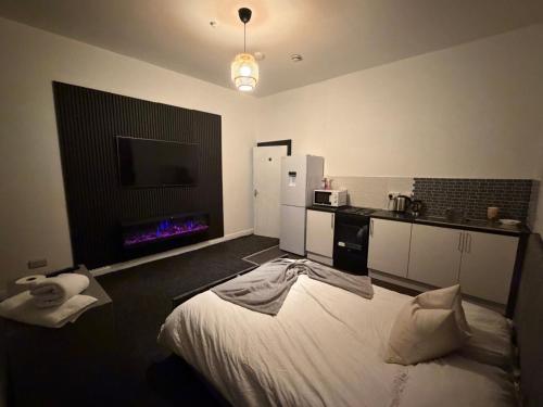een slaapkamer met een bed en een keuken met een tv bij Check Inn 247 in Bradford