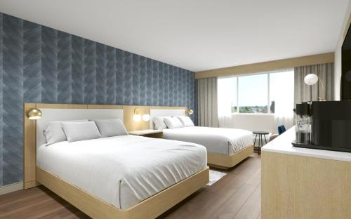 a hotel room with two beds and a television at Hotel Kelowna & Conference Centre in Kelowna