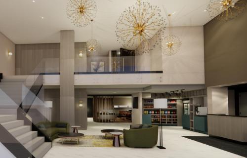 a lobby with a staircase and chairs and chandeliers at Hotel Kelowna & Conference Centre in Kelowna