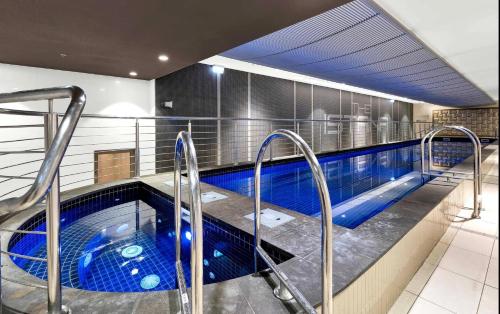 a large swimming pool with blue water in a building at Shared Apartment- private bedroom in Melbourne CBD in Melbourne