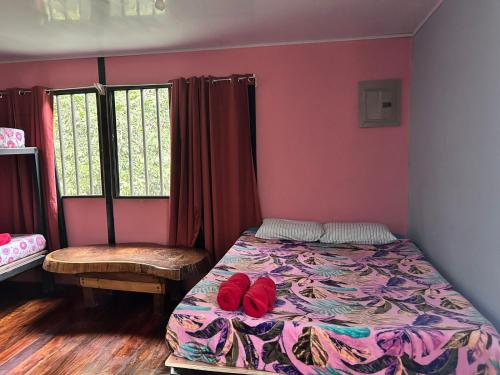 a bedroom with a bed with red shoes on it at Hospedaje el Argentico in Tapantí