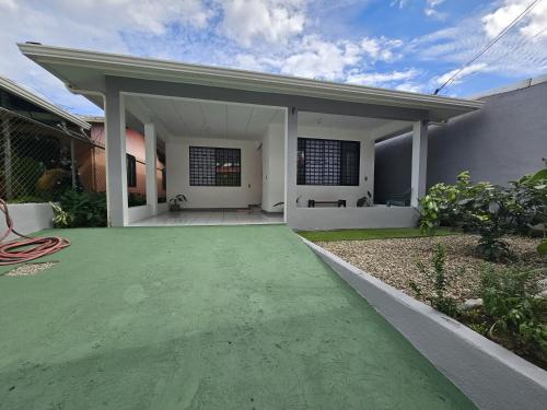 een wit huis met een groene oprit bij Casa Burbujas in Puerto Jiménez