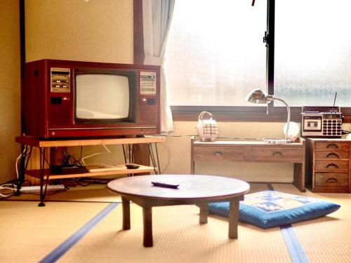 una cucina con una tv e un tavolo di fronte a un tavolo sidx sidx di 五縁箱 a Hannan