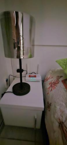 a white table with a lamp next to a bed at Flat Saigon Barra de Maricá Pé na Areia Wi-Fi in Maricá