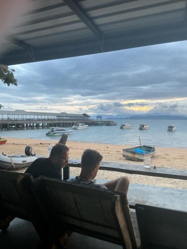 twee mannen zitten op een bankje vlakbij het strand bij Phayam Hostel in Ko Phayam