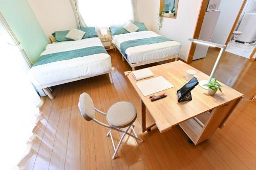 a room with two beds and a desk and a table at 民泊 Ichinomiya K Room 2B in Ichinomiya