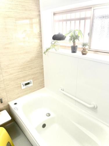 a white bathroom with a tub and a sink at 五縁箱 in Hannan