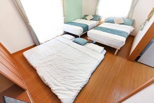three beds sitting in a room with wood floors at 民泊 Ichinomiya K Room 2B in Ichinomiya