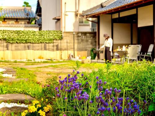 una persona in piedi in un giardino con un tavolo di 五縁箱 a Hannan