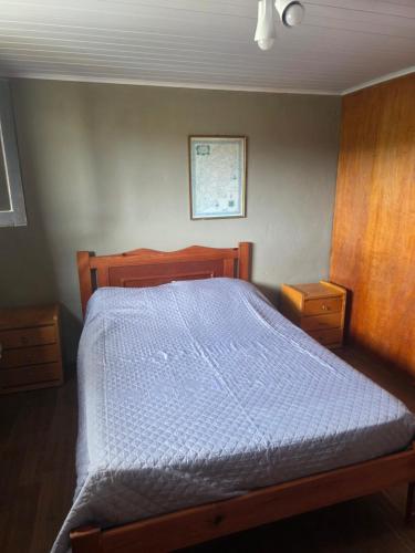 a bedroom with a wooden bed with a blue comforter at Mirador del Diablo in Punta Del Diablo