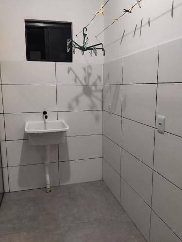 een badkamer met een wastafel en een tv aan de muur bij Casa temporada estrela do mar in Imbé