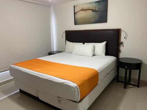 a bedroom with a large bed with an orange blanket at Hotel Presidente Tijuana in Tijuana