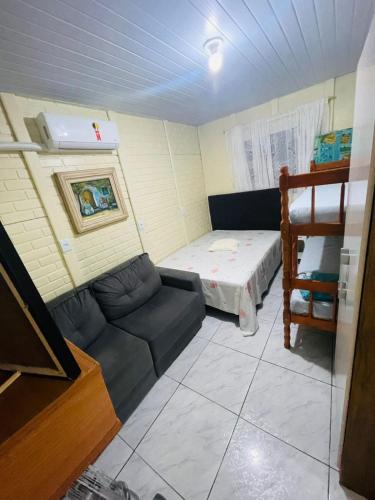 een kleine kamer met een bank en een bed bij Pousada do vô Bi 02 in São Francisco do Sul