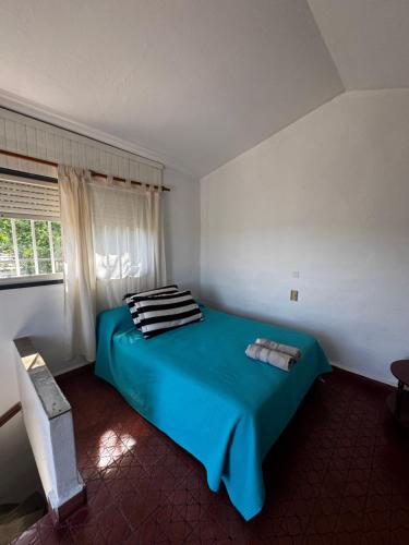ein blaues Bett in einem weißen Zimmer mit einem Fenster in der Unterkunft La Chuña in Villa Los Aromos