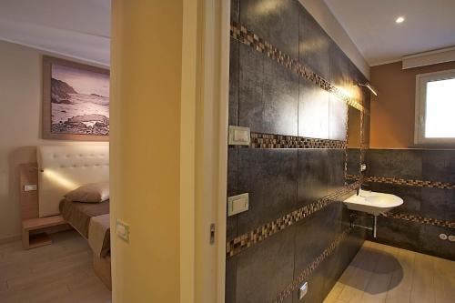a bathroom with a sink and a toilet and a bed at Hotel C'era Una Volta in Castiglione della Pescaia