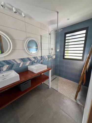 a bathroom with two sinks and a mirror at Maison dans la Forêt avec vue mer accès rivière in Goyave
