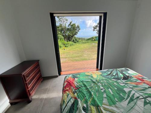 a bedroom with a bed and a large window at Maison dans la Forêt avec vue mer accès rivière in Goyave