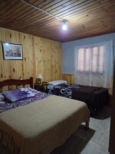 a bedroom with two beds and a wooden wall at Nido Rústico in Rivera