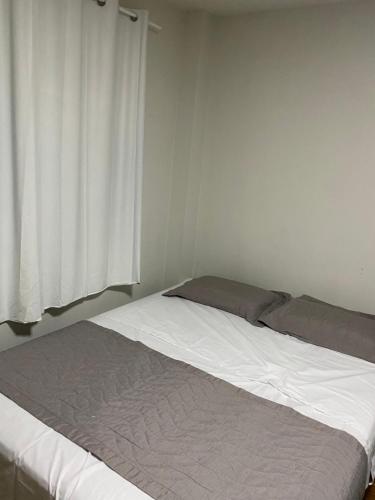 a bed in a white room with a window at San Juliano Studios in Foz do Iguaçu