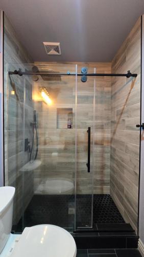 a glass shower in a bathroom with a toilet at Cozy Tiny Home For 2 People Studio Type in Norwalk