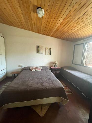 a bedroom with a large bed and a wooden ceiling at Alquiler temporal Colonia Caroya in Colonia Caroya