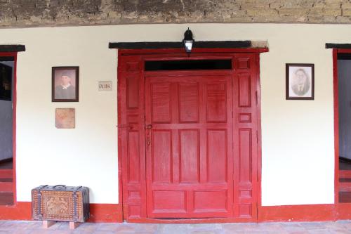 a red door in a white wall with pictures at Hotel Cacique Real in Zipaquirá