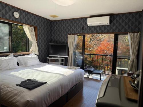 a bedroom with a large bed and a balcony at 箱根宿燕帰 in Hakone