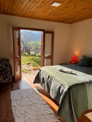 a bedroom with a bed and a large window at Pousada Morada Canto do Sol in São Bento do Sapucaí